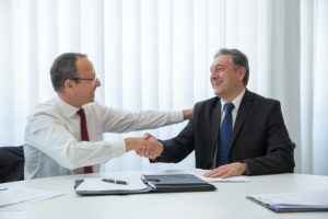 Two men shaking hands and discussing expert witness hourly rates