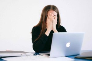 woman-with-hands-on-her-face-in-front-of-a-laptop