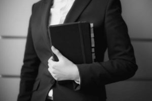 A Grayscale of a Woman in a Suit Holding a Planner with Label Tabs