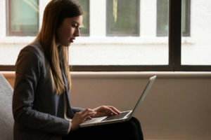 woman-sitting-down-and-using-laptop-on-her-lap
