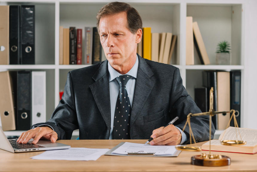 man-using-laptop-while-checking-paper-document