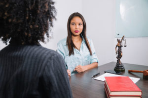Legal expert witness consulting with professional at table featuring law sculpture.