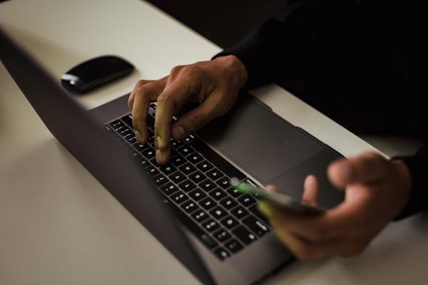 man-typing-on-laptop-and-using-smartphone-for-peekyou-removal