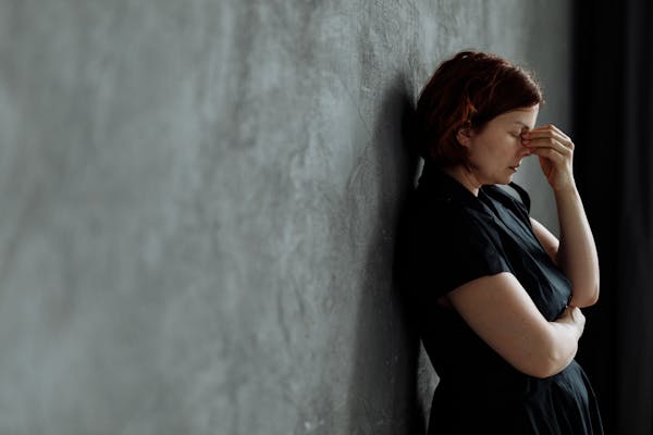 a-stressed-woman-leaning-on a-concrete-wall